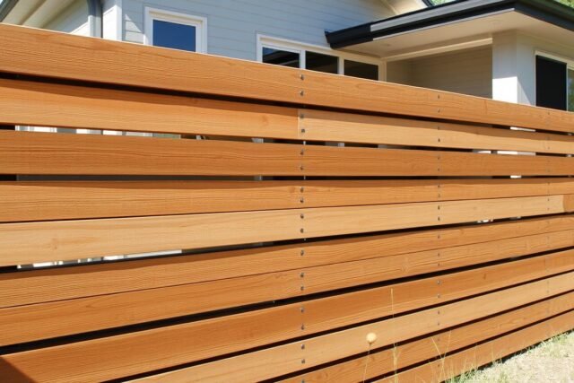 Modern horizontal slatted fence with mixed materials for 2025 design trends